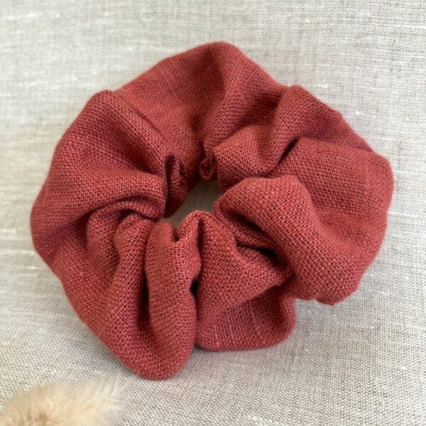 Chouchou en lin de couleur bruschetta posé sur du lin beige.