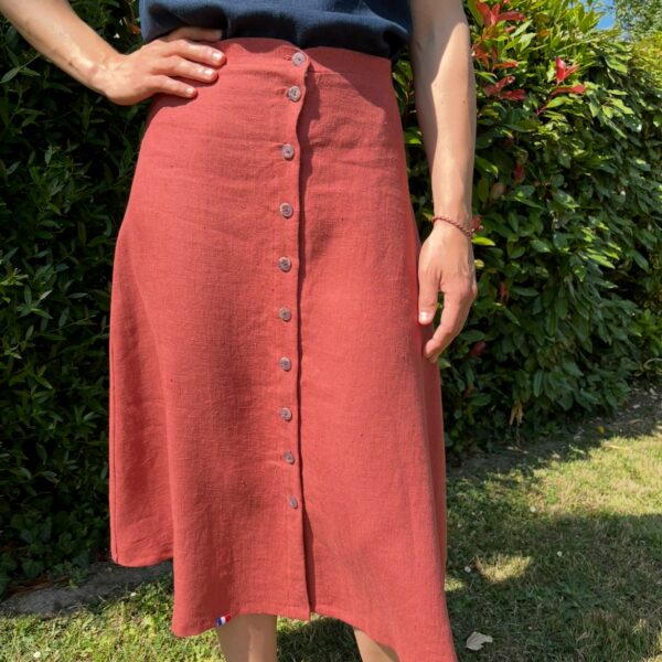 Jupe en lin de couleur bruschetta portée par une femme. Elle est fermée par 10 boutons gris tout le long du devant.