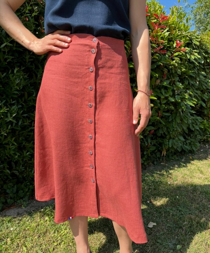 Jupe en lin de couleur bruschetta portée par une femme. Elle est fermée par 10 boutons gris tout le long du devant.