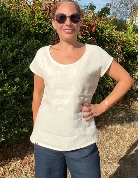 T-shirt crème vue de face sur une femme aux longs cheveux bouclés attachés par un chouchou.