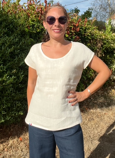 T-shirt crème vue de face sur une femme aux longs cheveux bouclés attachés par un chouchou.